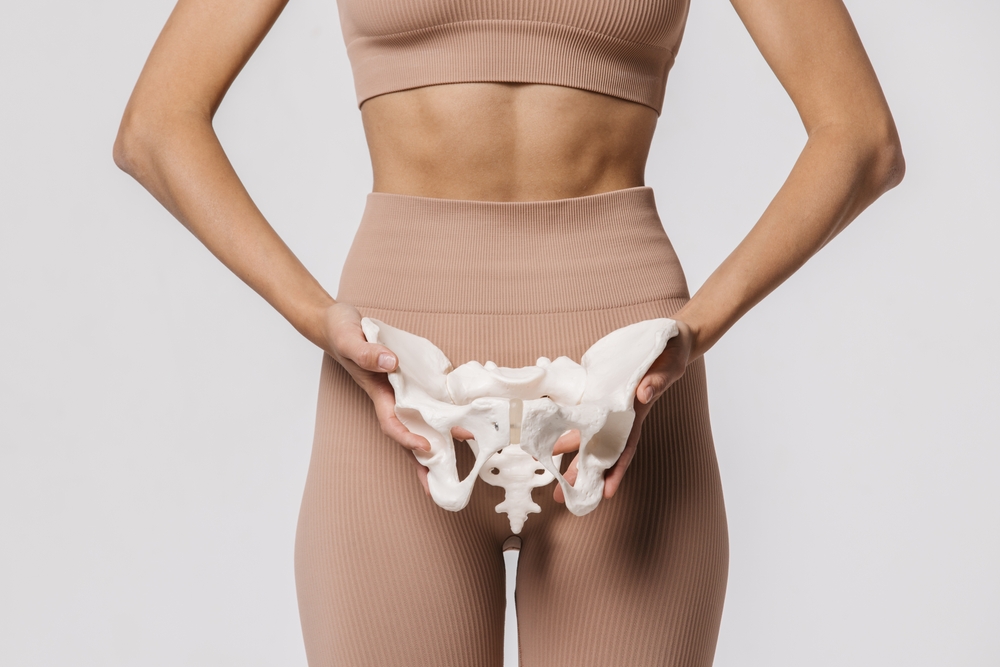 Close-up of the female pelvis in the hands of an athletic, healthy woman.