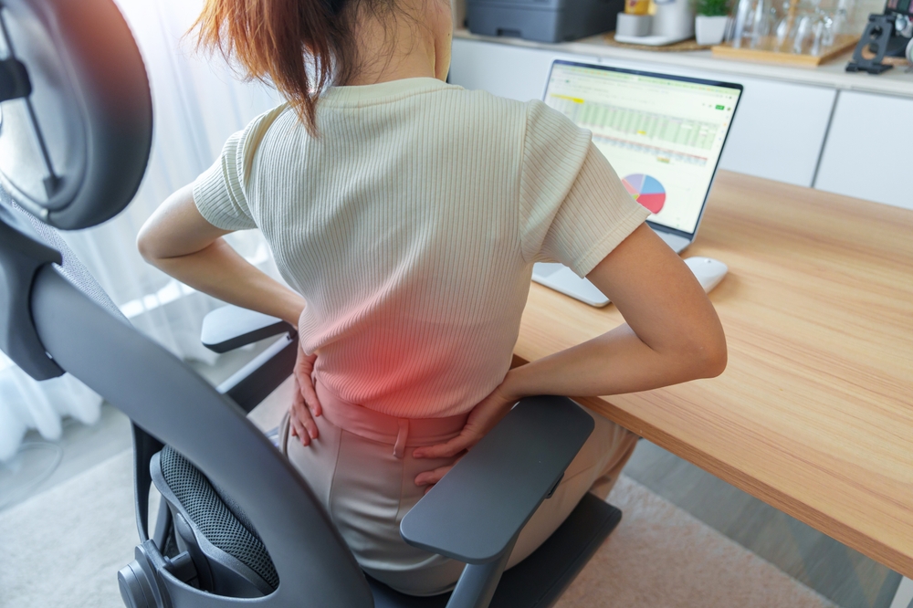 Woman having back body pain during work long time on workplace.